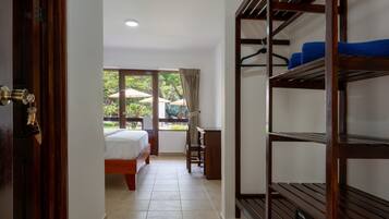 A hotel room with a bed, a desk, a chair, a window with curtains, and a view of the outdoors.