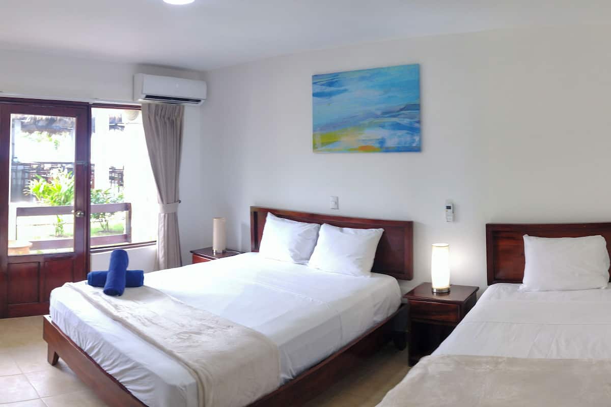 A hotel room with a large bed, a bedside table with a lamp, a painting on the wall, and a window with curtains.