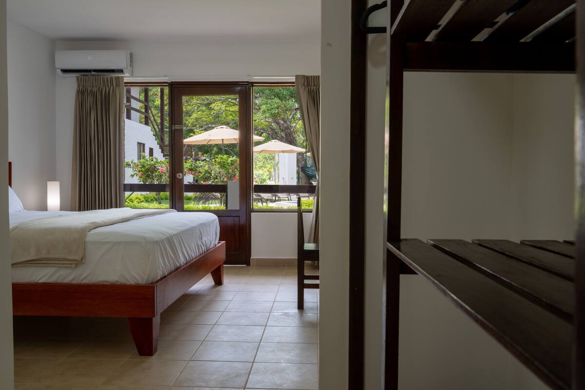 A bedroom with a bed, a chair, and a balcony with umbrellas.