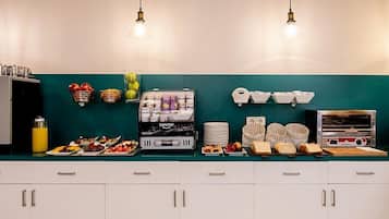 Una cocina con gabinetes blancos, salpicadero color aguamarina y diversos alimentos y electrodomésticos.