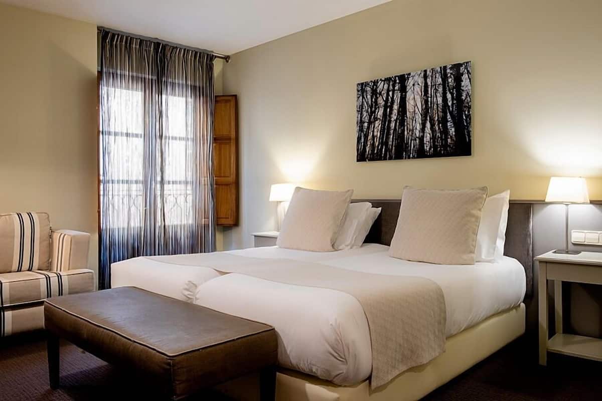 Una habitación de hotel con una cama grande, un sofá, una mesita y un cuadro en la pared.