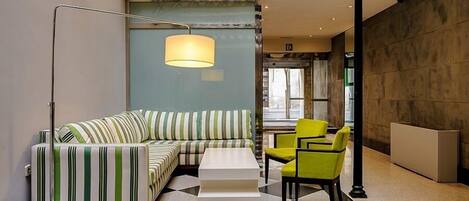 A modern lounge area with a striped sofa, a white coffee table, and a yellow chair.