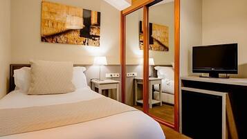 Une chambre d’hôtel avec un grand lit, une télévision, un bureau et un miroir.