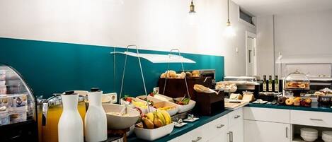 A buffet setup with various food items and beverages, including fruits, pastries, and condiments.