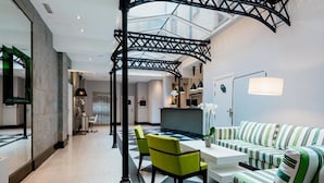 A modern interior with a central seating area, a glass ceiling, and a contemporary design. - Ikonik Plaza Mercado (Salamanca)
