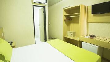 Ein Hotelzimmer mit einem Bett, einem Schreibtisch mit Stuhl, einem an der Wand montierten Fernseher und einem Kleiderschrank.