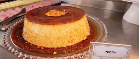 A dessert labeled 'PUDIM' on a metal serving tray with a name tag.