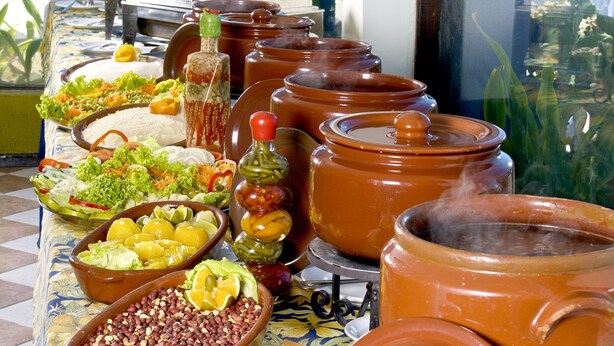 Una mesa de buffet con diversos platos y ollas grandes, probablemente para cocinar o servir comida.