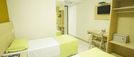 A hotel room with two single beds, a desk with a chair, a TV, and a wardrobe.