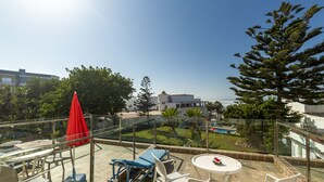 Una terraza en la azotea con mobiliario exterior, piscina y vistas del entorno.