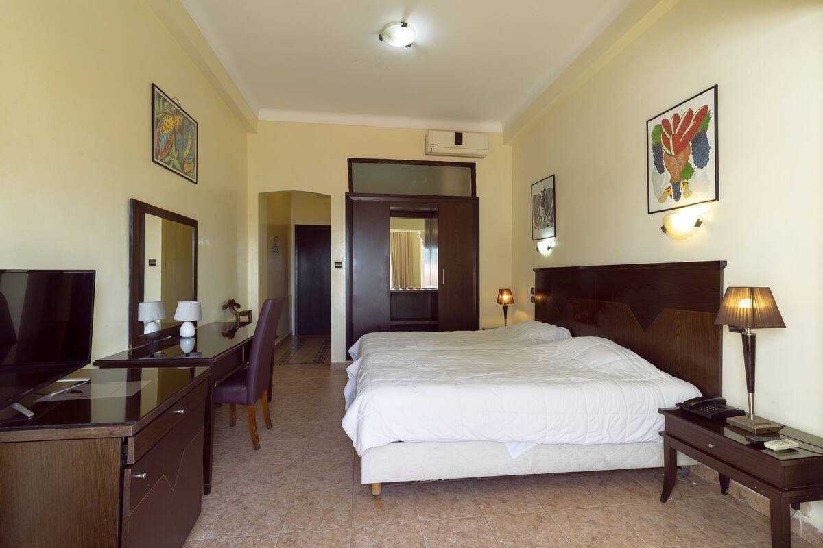 Een hotelkamer met een bed, bureau, stoel, televisie en kunst aan de muur.