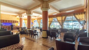 Un vestíbulo amplio con techos altos, grandes columnas y una zona de bar.