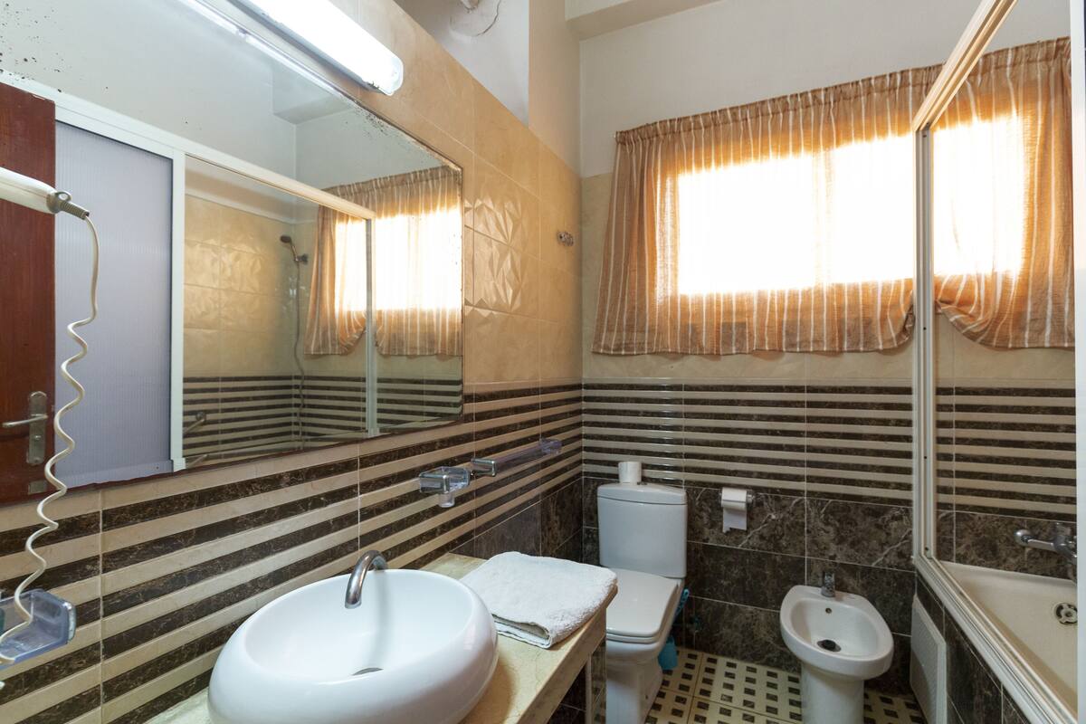 Een badkamer met een grote spiegel, een wastafel, een toilet en een bidet.