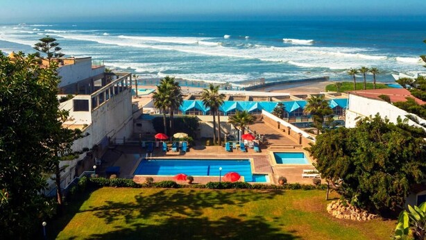 Un resort con piscina, palmeras y vista al océano.