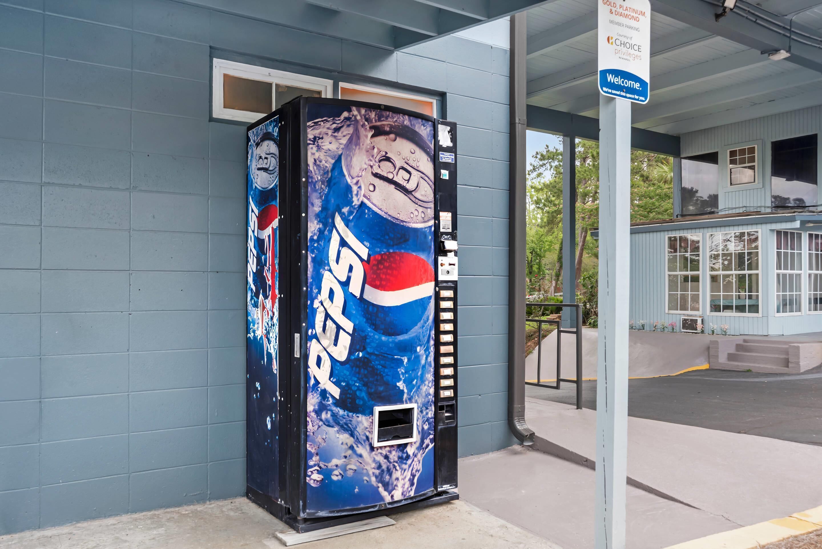 A vending machine with a Pepsi logo, a sign indicating member privileges, and a building entrance.