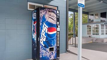 A vending machine with a Pepsi logo, a sign indicating member privileges, and a building entrance.