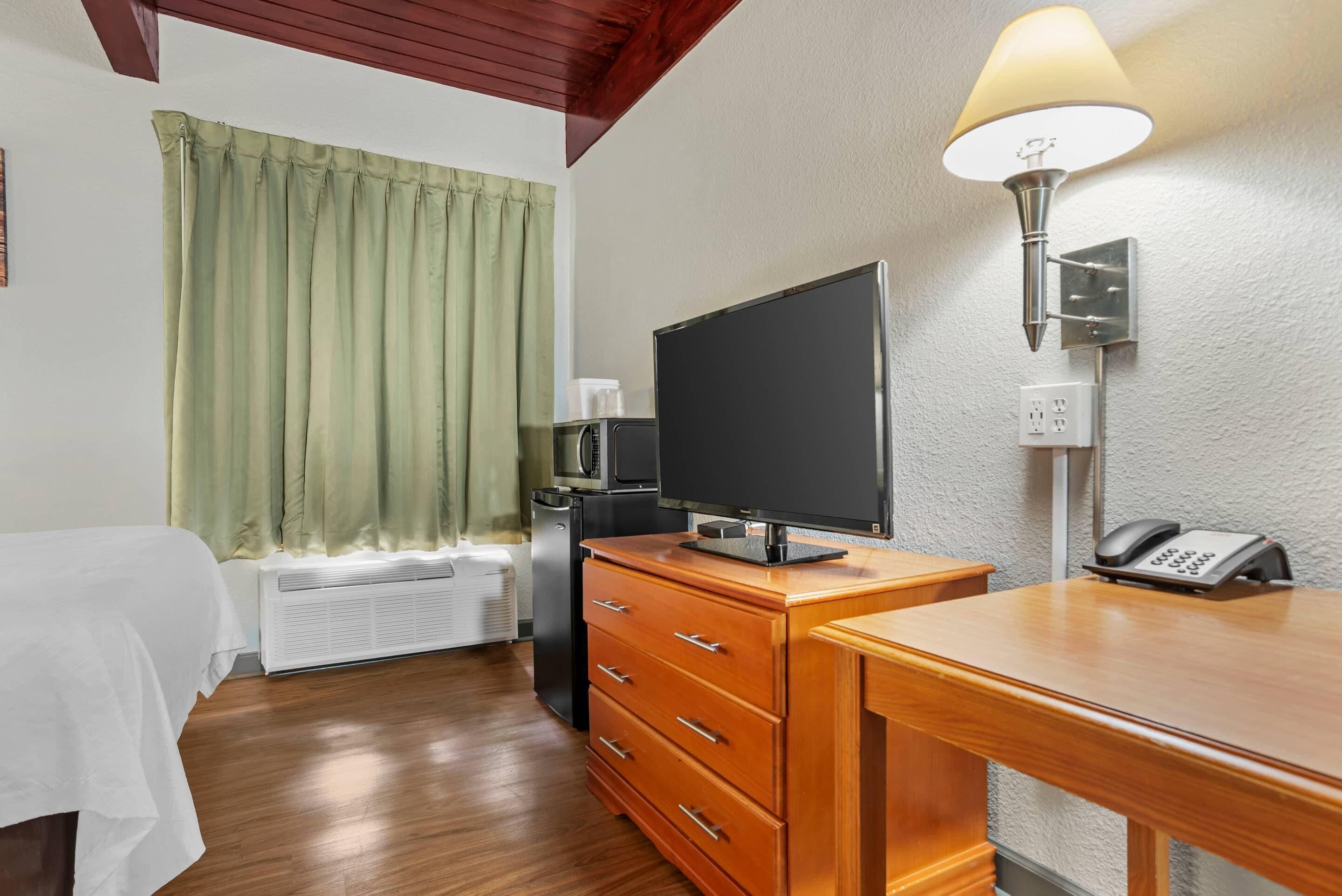 Une chambre d’hôtel équipée d’un lit, d’un bureau avec un téléphone, d’une télévision, d’un four à micro-ondes et d’un radiateur.