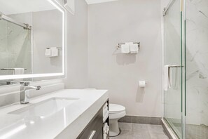 Une salle de bain moderne avec une douche à parois de verre, un lavabo blanc et des toilettes.
