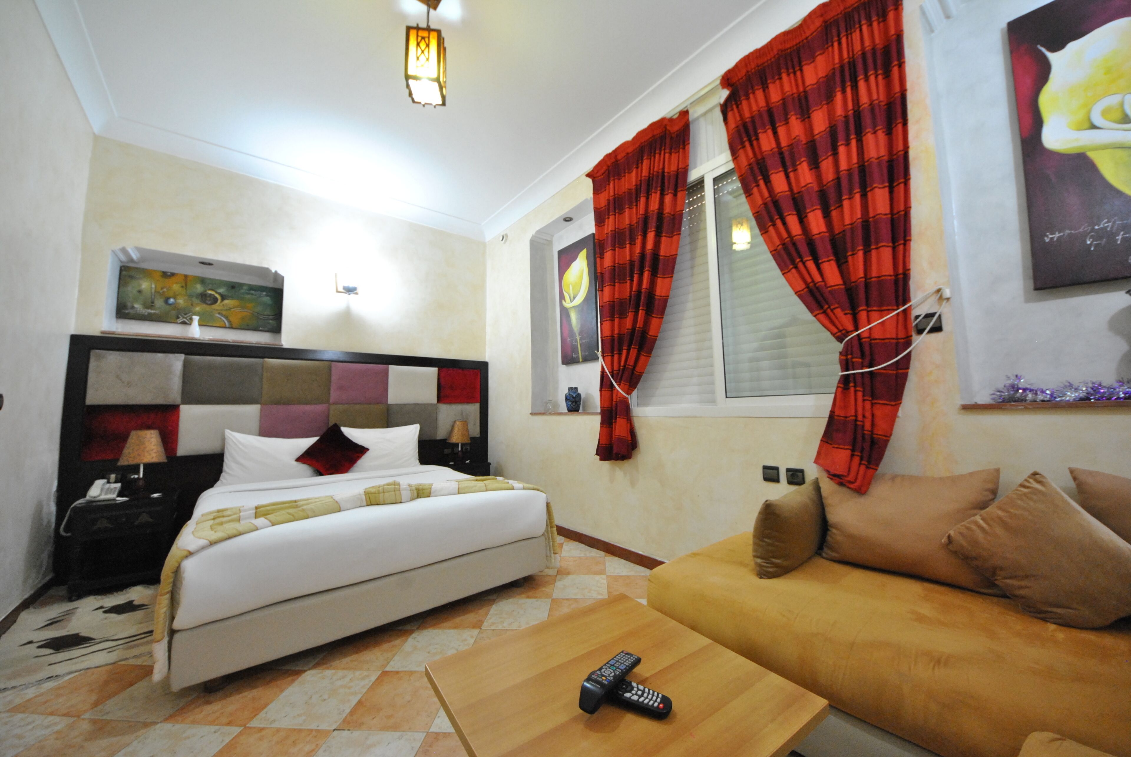 Una habitación de hotel con una cama, un sofá, una mesita de noche, una lámpara y un cuadro en la pared.