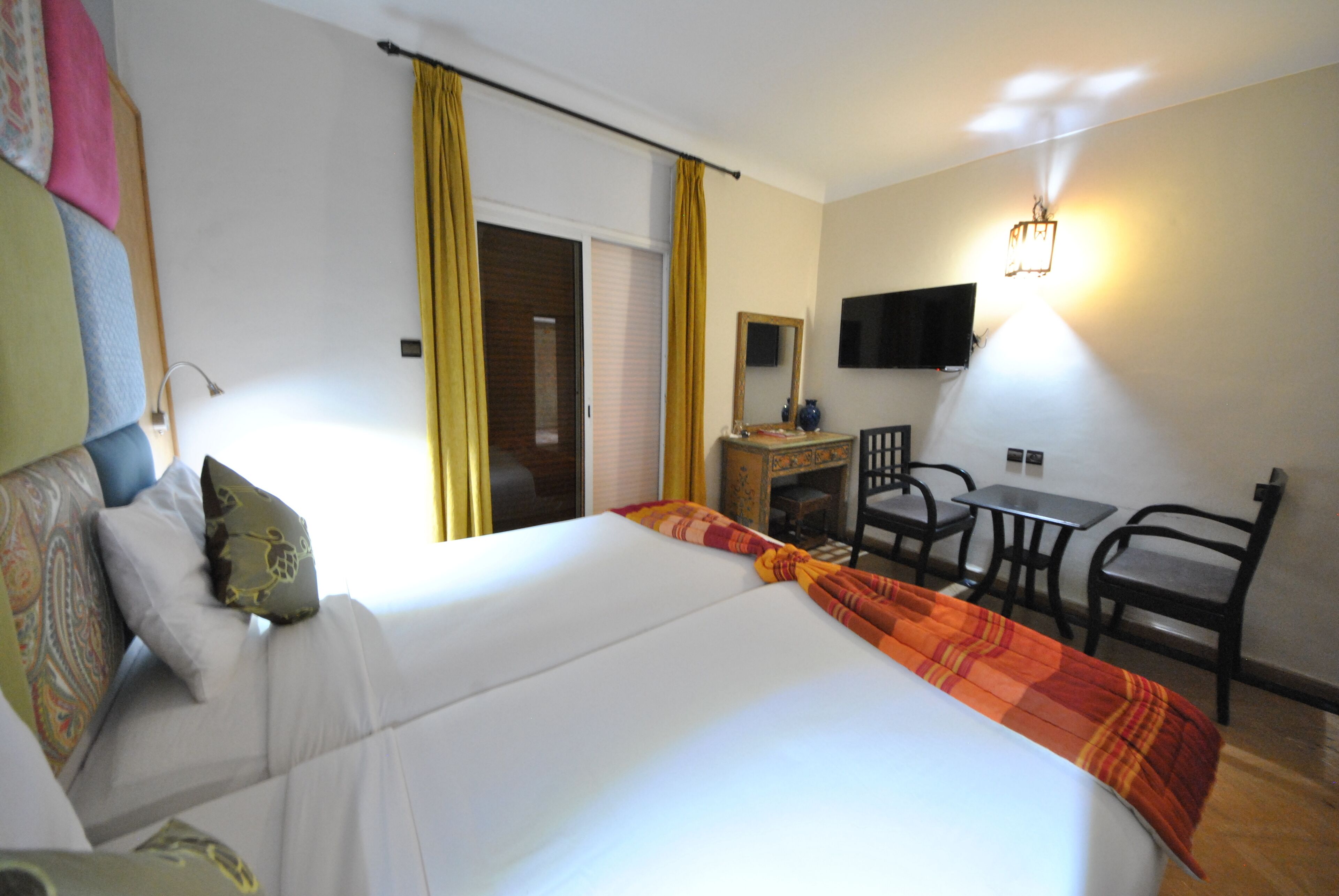 Hotelkamer met een groot bed, een bureau met stoel, een televisie aan de muur en een raam met gordijnen.