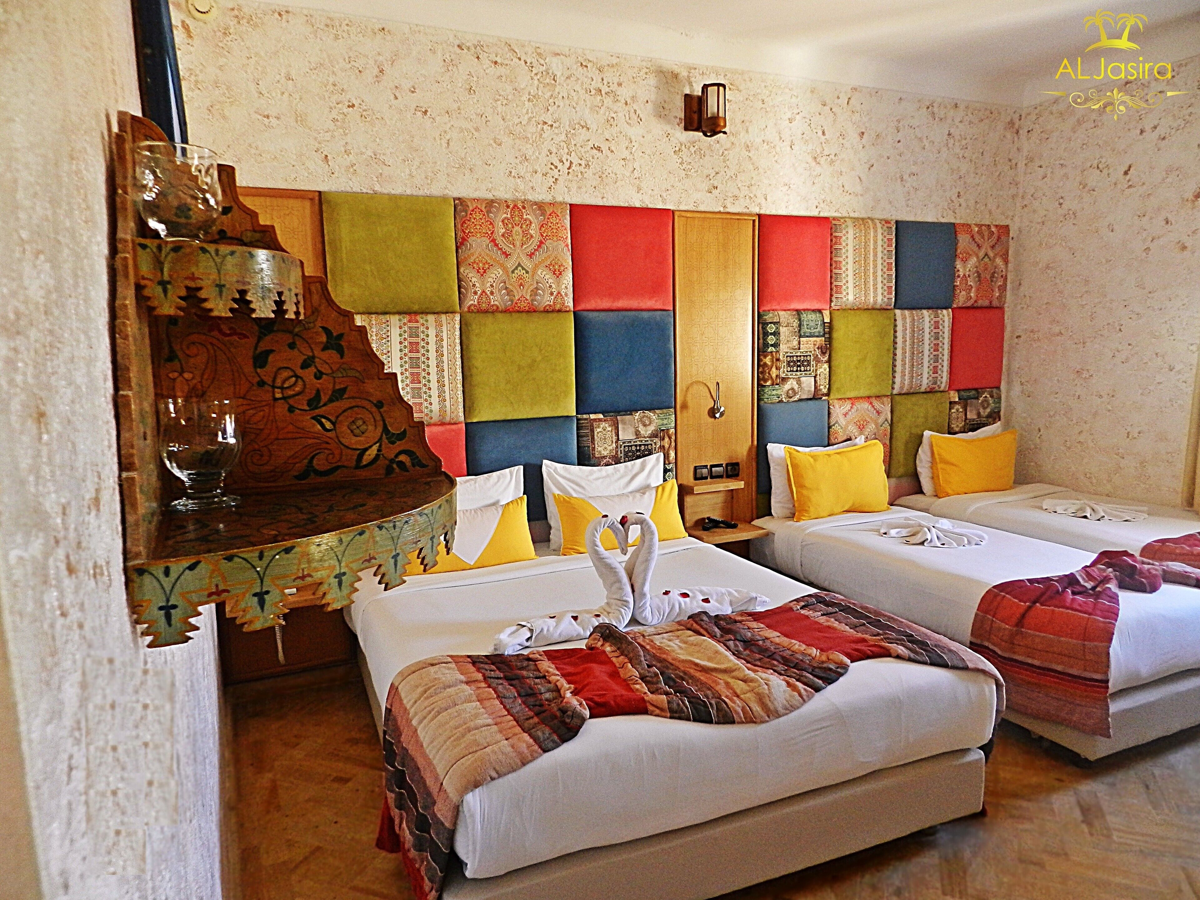 Habitación de hotel con dos camas, cabecero de madera y un panel decorativo en la pared.