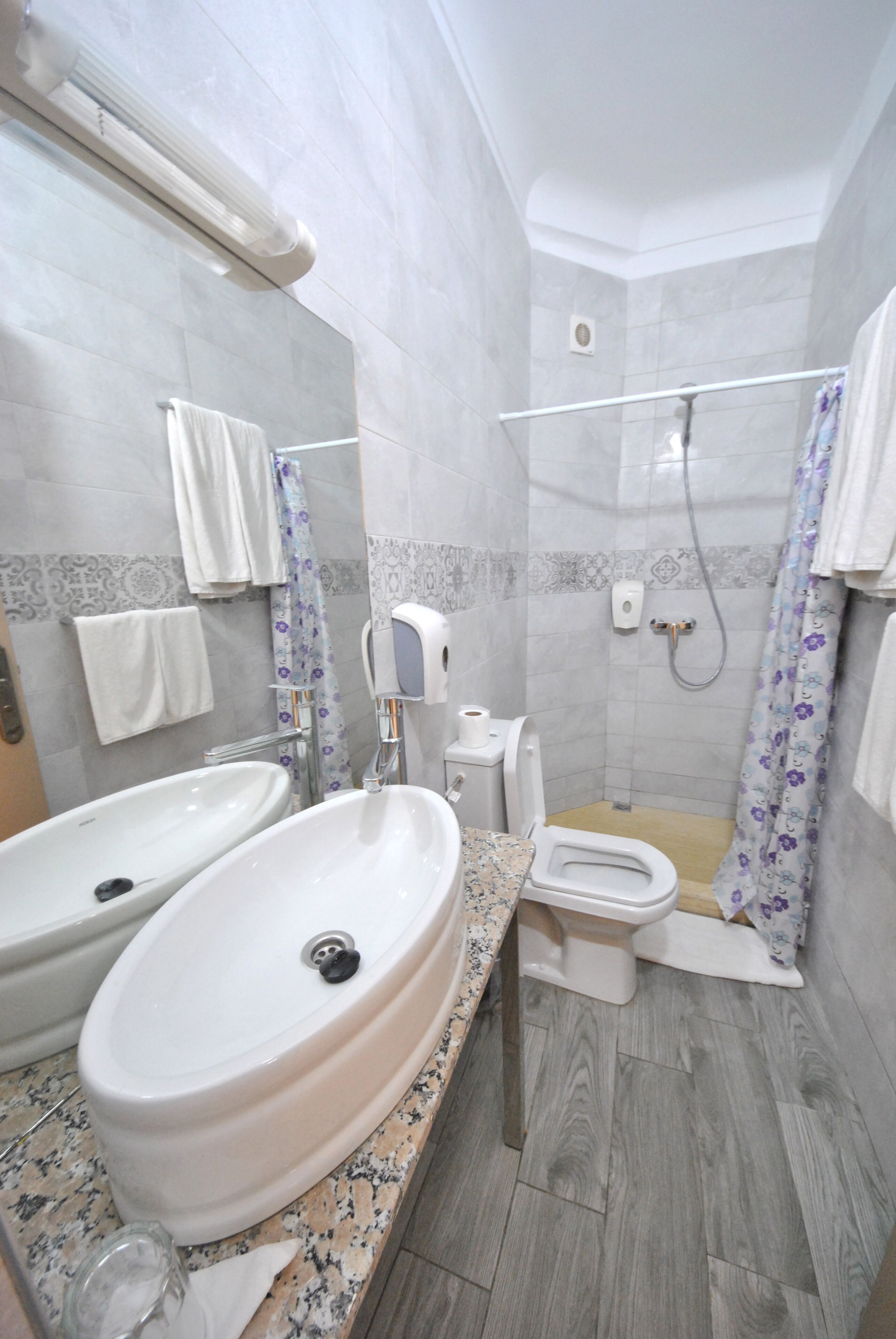 Un baño con dos lavamanos, un inodoro, una ducha y un espejo.