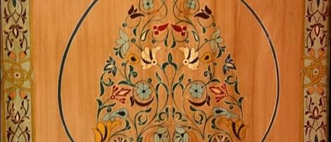 A wooden door with intricate floral and geometric patterns, a number '243' above it, and a handle on the left.