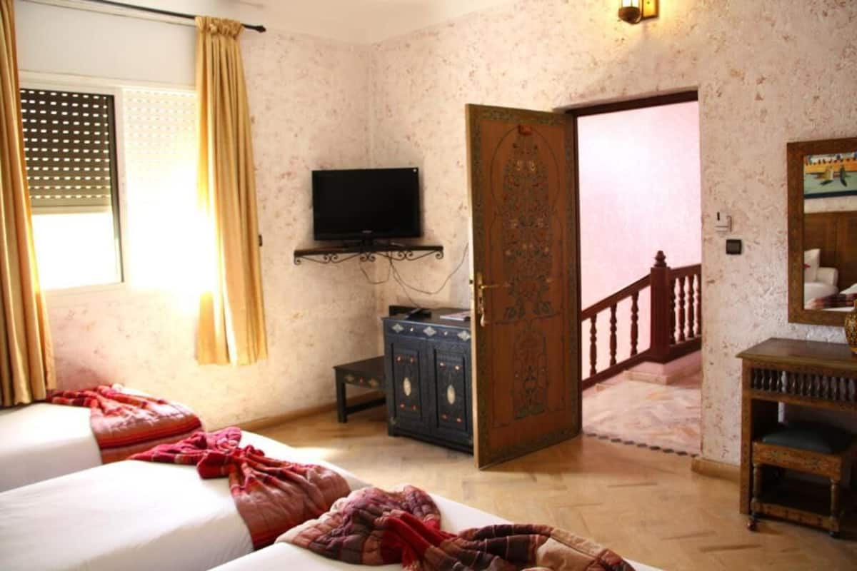 Un dormitorio con dos camas, un televisor, un armario y una puerta que da a otra habitación.