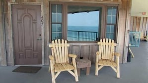 Een houten gevel met een deur waarop '405' staat, twee houten Adirondack-stoelen en een kleine tafel.