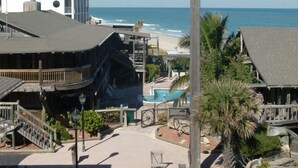 Een resort met een zwembad, uitzicht op het strand en een gebouw met een uniek architectuurontwerp.