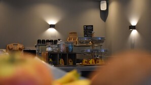 Un área de cocina con cafetera, frascos de condimentos y una exhibición de frutas.