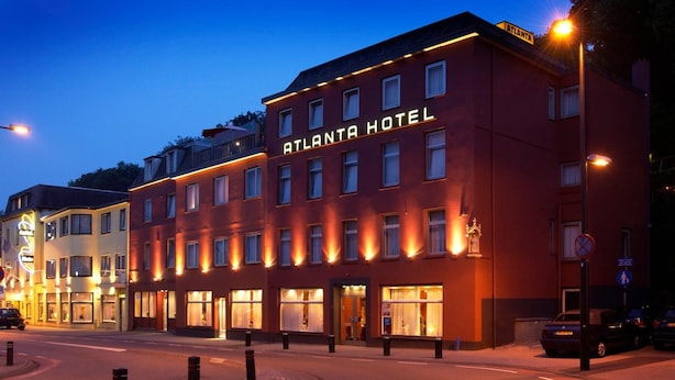 Un hotel con un letrero llamativo que dice "ATLANTA HOTEL" y múltiples ventanas con interiores iluminados.