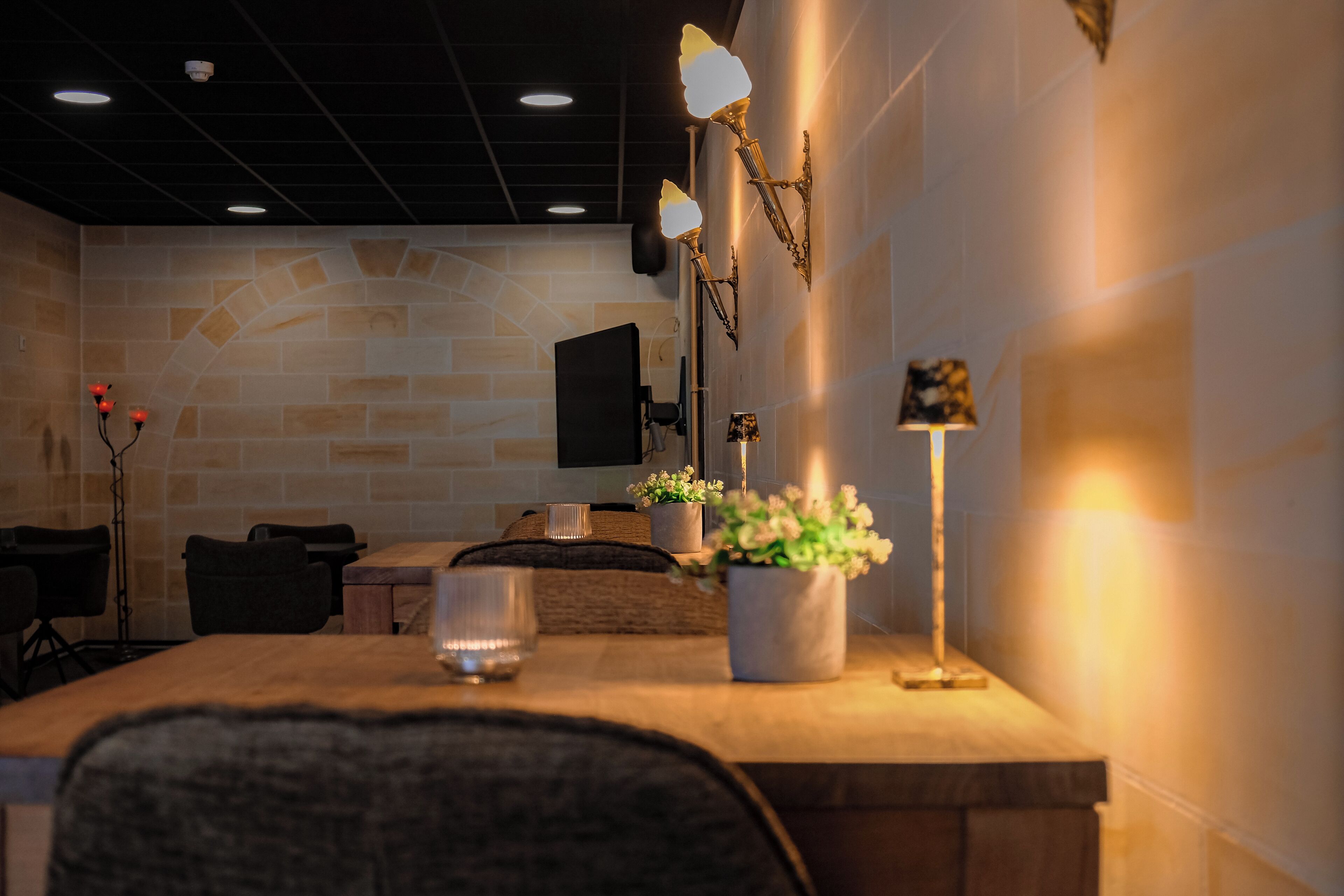 A restaurant with a stone wall, wooden tables, and a potted plant.
