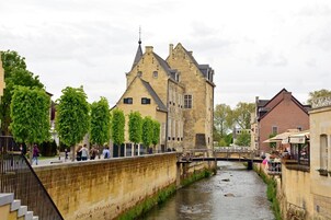 A historic building with a stone facade, a bridge, and a narrow waterway.