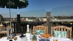 Mesa de comedor al aire libre con una botella de champán, una taza de café y un plato de pasteles.
