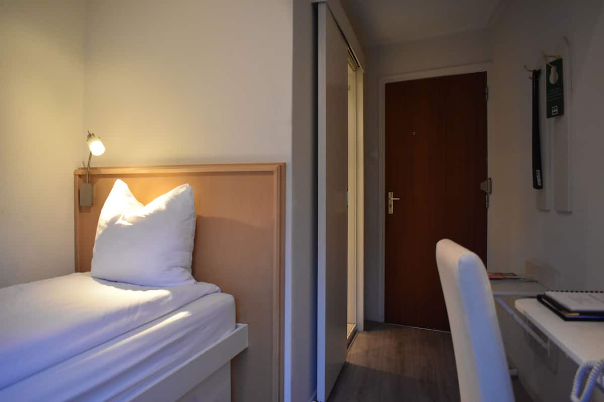 Una habitación de hotel con una cama, un escritorio y una silla.