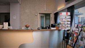 A reception desk with a modern design, a potted plant, and a bulletin board with pamphlets. - Hotel 2000 (Valkenburg aan de Geul)