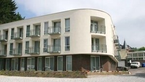 A multi-story building with balconies, a parking area, and a gravel driveway. - Hotel 2000 (Valkenburg aan de Geul)