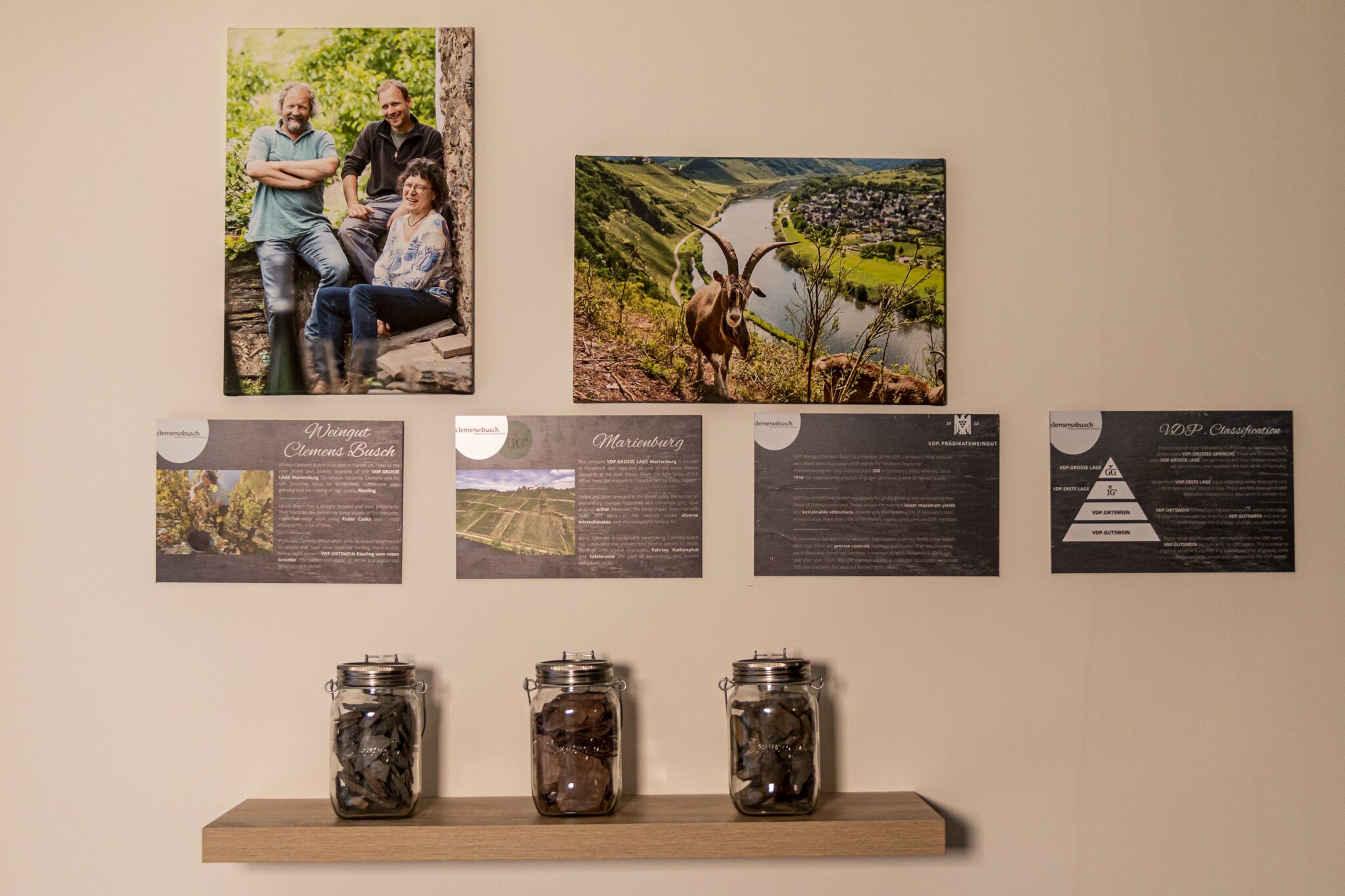 A wall with framed photos, informational posters, and three jars on a shelf.