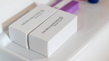 Zwei weiße Boxen mit der Aufschrift 'The Spa Collection Shower Cap' auf einer weißen Oberfläche.