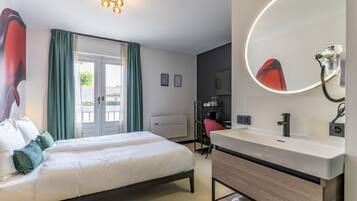 A hotel room with a bed, a bathroom with a mirror, and a view of the outside.