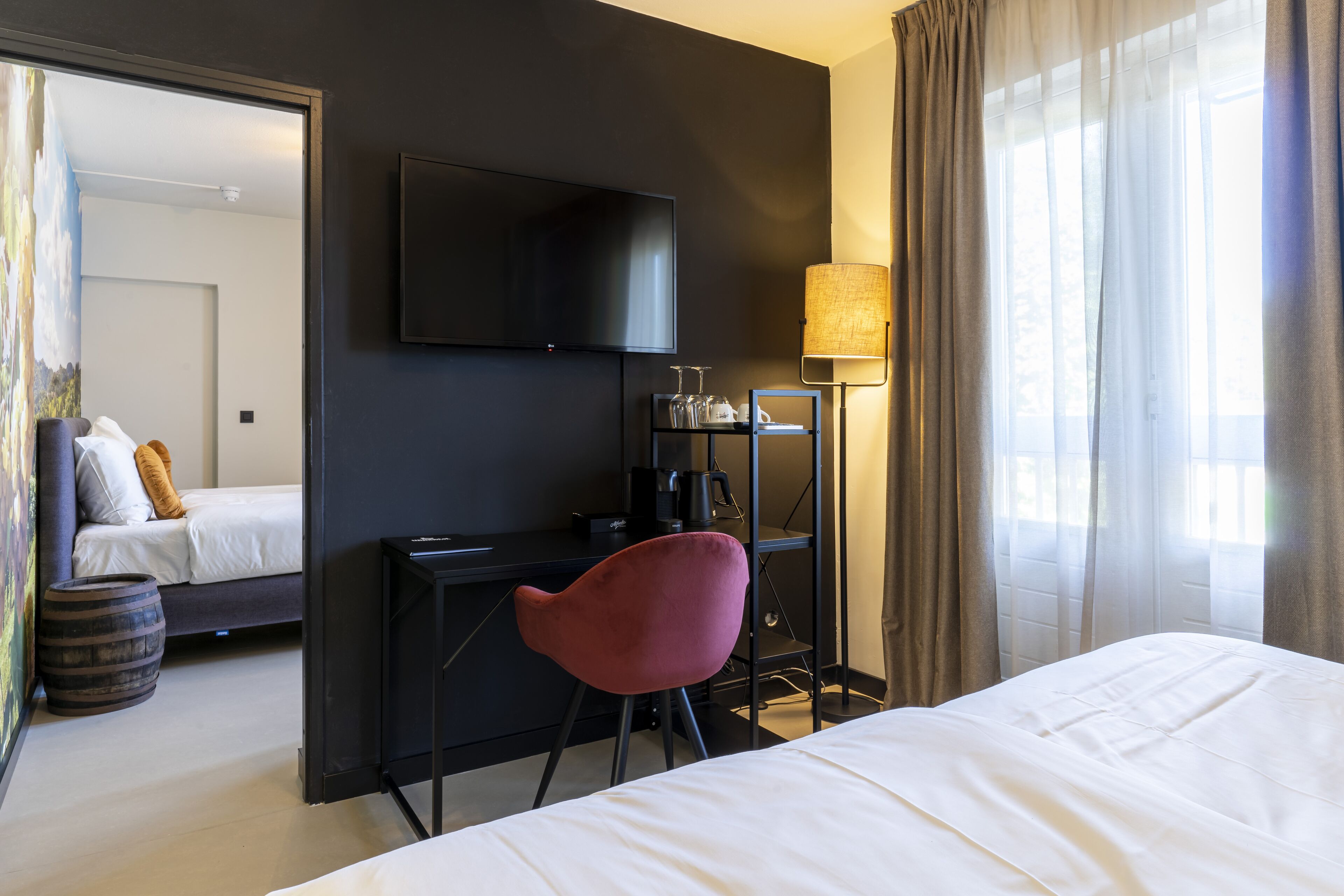 Una habitación de hotel con cama, escritorio, silla, televisor y lámpara.