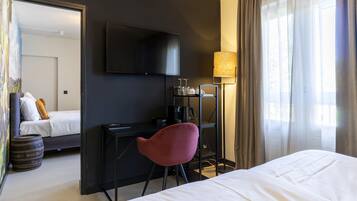 Una habitación de hotel con cama, escritorio, silla, televisor y lámpara.
