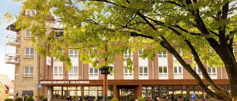 A hotel with outdoor seating and a clear view of the building's facade.