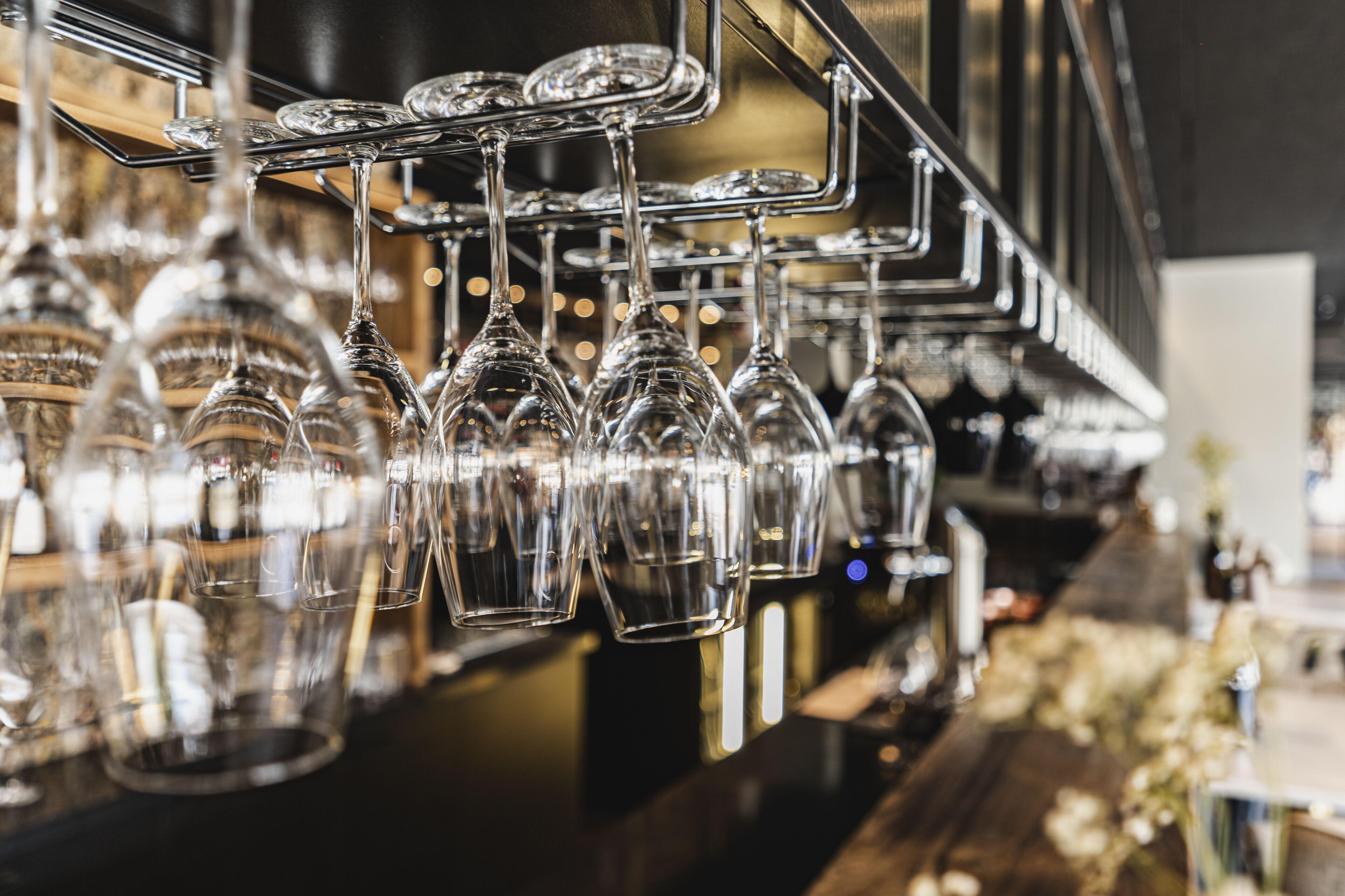 Un espace bar agrémenté de plusieurs verres à vin suspendus et d’un comptoir.