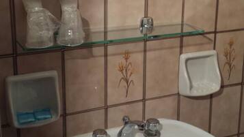 A bathroom with a white sink, a glass shelf, a mirror, and a towel rack.