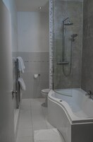 Un baño moderno con ducha envuelta en vidrio, una bañera independiente y un inodoro.
