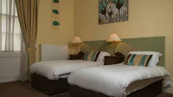 A double bed with two bedside tables, a radiator, and a window with curtains.