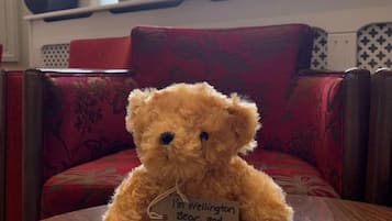 Un oso de peluche sobre una mesa de madera con una etiqueta que dice 'Soy Wellington Bear, y esta es mi silla número 2 metros'.