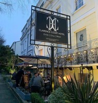 The exterior of Clarence Court Hotel with a signboard advertising services like drink, dine, and meet.